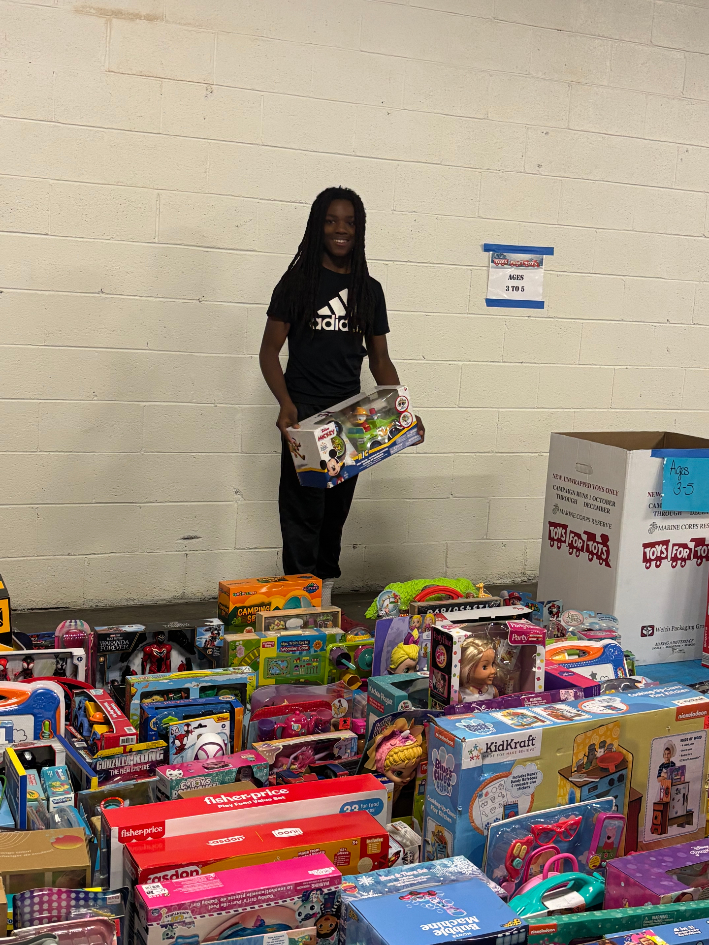 Young Kingdom Changers volunteer standing among donated toys